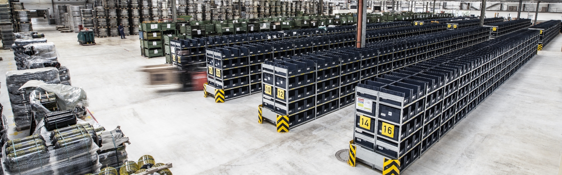 Großes Logistiklager mit langen Regalreihen und sortierten Transportbehältern